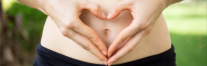 Woman holding her hands in a heart shape over her gut